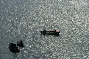 Trois petit bateaux dans le l'eau avec le Soleil brillant sur il photo