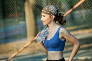 sportif Jeune femme dans tenue de sport Faire élongation des exercices en plein air. portrait de une Jeune fille Faire sport dans le parc. photo