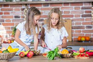 deux peu les filles dans le cuisine avec Frais des légumes. en bonne santé nourriture concept.. content sœurs photo