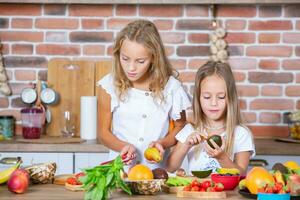 deux peu les filles dans le cuisine avec Frais des légumes. en bonne santé nourriture concept. content sœurs. photo