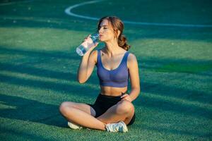 sportif Jeune femme dans tenue de sport Faire élongation des exercices en plein air. portrait de une Jeune fille Faire sport dans le parc. photo