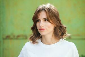 portrait de une magnifique Jeune femme avec longue marron cheveux souriant à le caméra photo