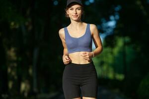 sportif Jeune femme dans tenue de sport Faire élongation des exercices en plein air. portrait de une Jeune fille Faire sport dans le parc. photo