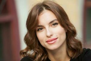 portrait de une magnifique Jeune femme avec longue marron cheveux souriant à le caméra photo