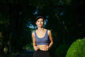 sportif Jeune femme dans tenue de sport Faire élongation des exercices en plein air. portrait de une Jeune fille Faire sport dans le parc. photo