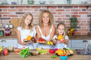 mère et filles cuisine ensemble dans le cuisine. en bonne santé nourriture concept. portrait de content famille avec Frais smoothies. content sœurs. photo