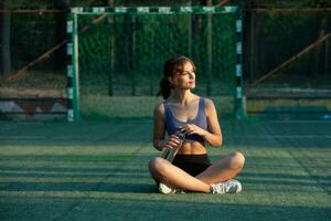 sportif Jeune femme dans tenue de sport Faire élongation des exercices en plein air. portrait de une Jeune fille Faire sport dans le parc. photo