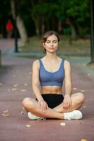 sportif Jeune femme dans tenue de sport Faire élongation des exercices en plein air. portrait de une Jeune fille Faire sport dans le parc. photo