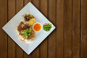 Haut vue cuit porc jambe sur riz avec une bouilli Oeuf sur le marron en bois tableau. photo