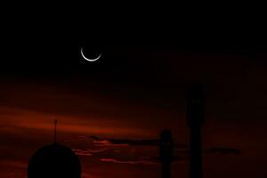 concept le croissant de lune le symbole de l'islam commence l'aïd al fitr. voir la lune dans le ciel nocturne. le ciel du soir et le vaste fleuve dans l'obscurité sont magnifiques. photo