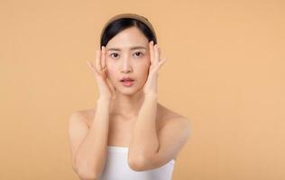 magnifique fille asiatique modèle émouvant Frais embrasé hydraté faciale peau sur beige Contexte fermer. beauté visage Jeune femme avec Naturel maquillage et en bonne santé peau portrait. peau se soucier concept photo