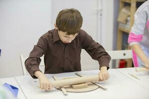 une peu garçon apprend à sculpter de argile. photo