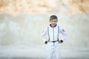 une Jeune garçon habillé comme un astronaute contre le toile de fond de blanc montagnes. photo