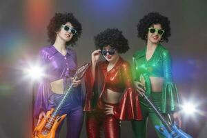 disco les filles dans ancien style avec jouet guitares dans le des rayons de étape lumière. photo