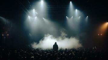 silhouette de une effrayant homme dans capuche à de face de une foule à une foncé concert. photo