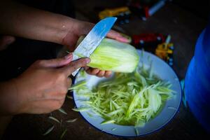 une femme main en portant une couteau est couper Papaye pour cuisson. photo