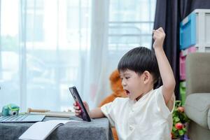asiatique garçon en portant en haut mains à communiquer avec copains dans en ligne salle de cours via mobile téléphone photo