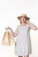 49 ans vieux femme client dans blanc robe en portant deux artisanat papier achats Sacs dans un main photo