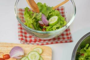 cuisine - femme fabrication Frais biologique légume salade dans le cuisine. femelle mains en train de préparer délicieux en bonne santé nourriture à maison, mélange des légumes dans une bol, fermer. photo