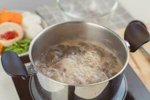 fait maison bouillon recette. du chef mains en train de préparer porc nervure Stock avec des légumes dans le pot. cuisinier dans le cuisine. photo