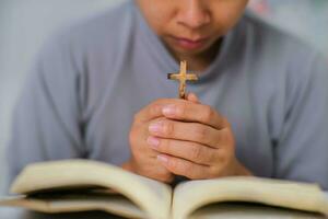 fermer de une femme en train de lire un ouvert Bible, prier et en portant mains sur sa Bible. spirituel ou Bible étude concept. photo