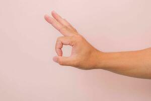 Masculin main montrant d'accord geste isolé sur rose Contexte. photo