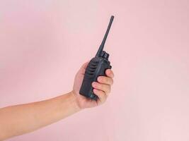 proche en haut main en portant portable walkie talkie isolé sur rose Contexte. noir ordinateur de poche walkie talkie photo