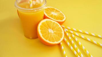 jus d'orange dans une tasse fermée de restauration rapide avec tube sur fond jaune photo