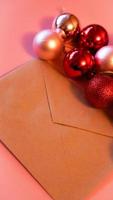 enveloppe de papier kraft avec des boules de noël rouges et roses sur rose photo