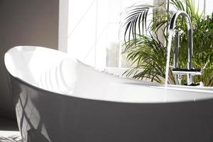salle de bain moderne. bain blanc avec des branches de palmiers verts photo