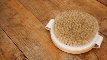 brosse de massage à sec en matériaux naturels sur fond de bois photo