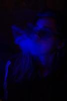 Close up portrait of vaping girl in neon blue light
