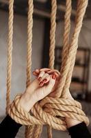 attaché avec une corde mains féminines avec des ongles rouges photo