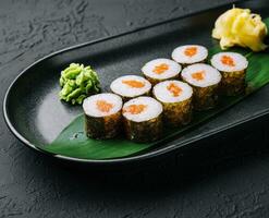 rangée de Frais maki Sushi Rouleaux sur noir assiette photo