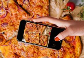 femelle main fabrication une photo de Pizza avec une mobile téléphone