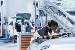 mécanicien dans voiture un service cueillette couple clé de travail station banc, en utilisant il à serrer boulons après remplacer moteur. africain américain garage ouvrier les usages professionnel outils à réparer client voiture photo