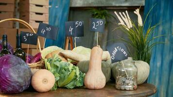 en bois table rempli avec saisonnier des fruits et légumes, vide stalle avec pièces de monnaie pot pour des dons. vide Les agriculteurs marché compteur avec biologique Naturel produire de jardin. ordinateur de poche tir. photo