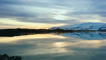 Lac et neigeux montagnes dans Islande avec magnifique paysage, gelé du froid l'eau. scandinave la nature paysage avec collines et des champs, panoramique vue scénique itinéraire. ordinateur de poche tir. photo