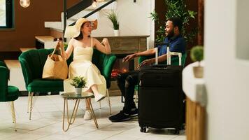 touristes séance dans salon zone à Hôtel lobby, attendre à faire vérifier dans processus et remplir dans enregistrement formes. couple sur voyage de noces vacances en arrivant à exotique bord de mer station balnéaire, la conciergerie prestations de service. photo