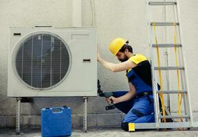 compétent dépanneur départ travail sur défectueux air Conditionneur, en utilisant ordinateur de poche percer à démonter condenseur métal bobine panneau. précis mécanicien démantèlement HVAC système à vérifier pour saleté photo