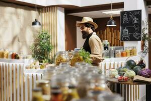 homme dans zéro déchets boutique remplissage achats panier avec en bonne santé localement grandi des légumes. écologiquement responsable client achat biologique non organisme génétiquement modifié nourriture de local quartier magasin photo