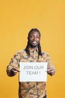 africain américain heure recruteur en portant emploi offre signe, embauche candidat pour affaires carrière opportunité permanent dans studio plus de Jaune Contexte. publicité avec emploi application photo