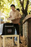 Jeune adulte avec sac à dos livrer biologique produire dans boîte, en train de préparer à prendre Naturel nourriture commande à clients. femme livraison courrier cueillette en haut commande de local marché rester. photo