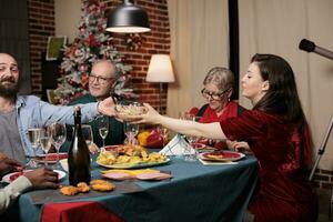 famille en mangeant de fête repas à dîner, célébrer Noël veille ensemble et qui passe nourriture assiettes autour le tableau. de bonne humeur gens réunion pendant Noël fête vacances, fête festin. photo