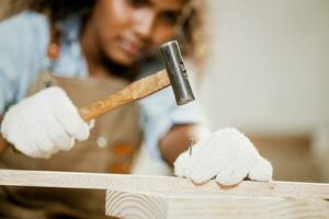 fermer bois ouvrier Charpentier utilisation marteau outil avec ongles pour Fait main en bois meubles dans atelier. photo