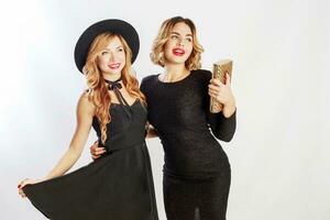 fête temps de deux meilleur amis, blond femmes dans noir cocktail élégant robe posant dans studio sur blanc Contexte. photo