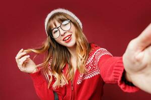 souriant femme dans hiver tenue posant dans studio sur rouge Contexte. photo