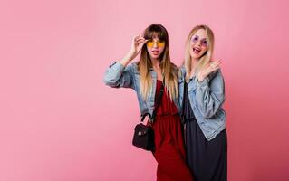 mode de vie portrait de deux branché les filles meilleur copains avec brillant faire en haut , fabrication marrant visages et Envoi en cours baiser plus de rose Contexte. photo