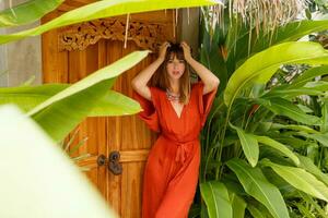 magnifique brunette femme dans élégant été tenue enjoing vacances dans luxe station balnéaire. exotique jardin avec tropical les plantes. photo