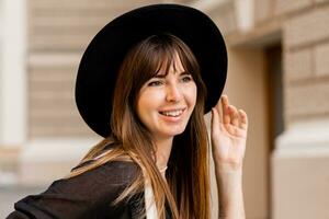 proche en haut portrait de élégant brunette femme dans décontractée tenue et noir chapeau. enjoing vacances dans européen ville. photo